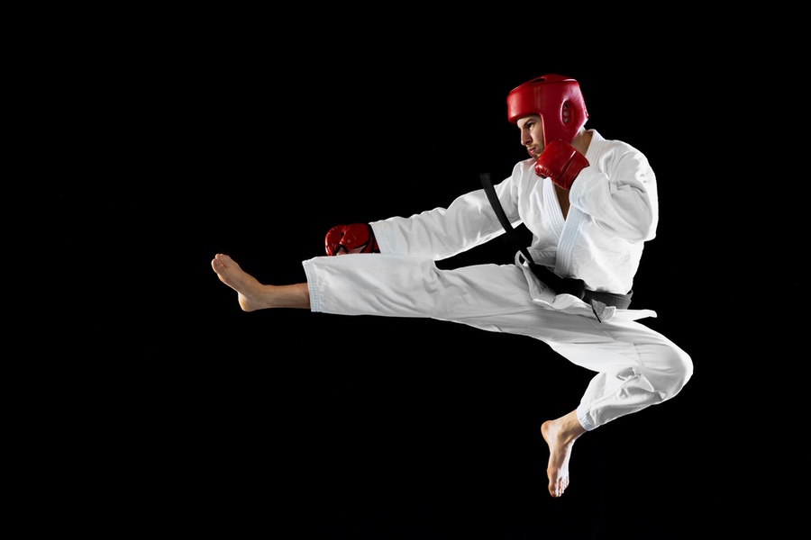 Portrait of professional sportsman training, practising karate isolated over black studio background