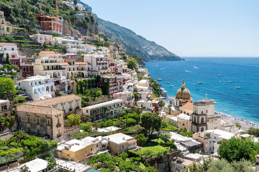 Street scape of Positano, located on the Tyrrhenian sea coast, Italy. Rows of residential buildings, church, greenery, beach